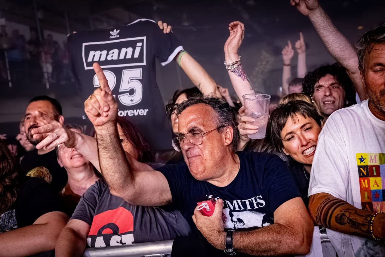 A fan holds an adidas Mani 25 Forever shirt above the crowd.
