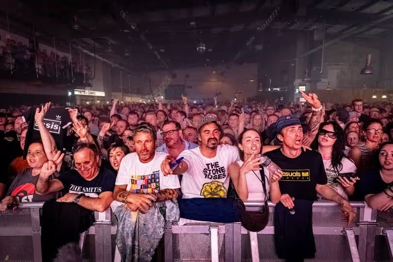 The crowd from the stage: Stone Roses, Smiths and Oasis shirts along the front rail.