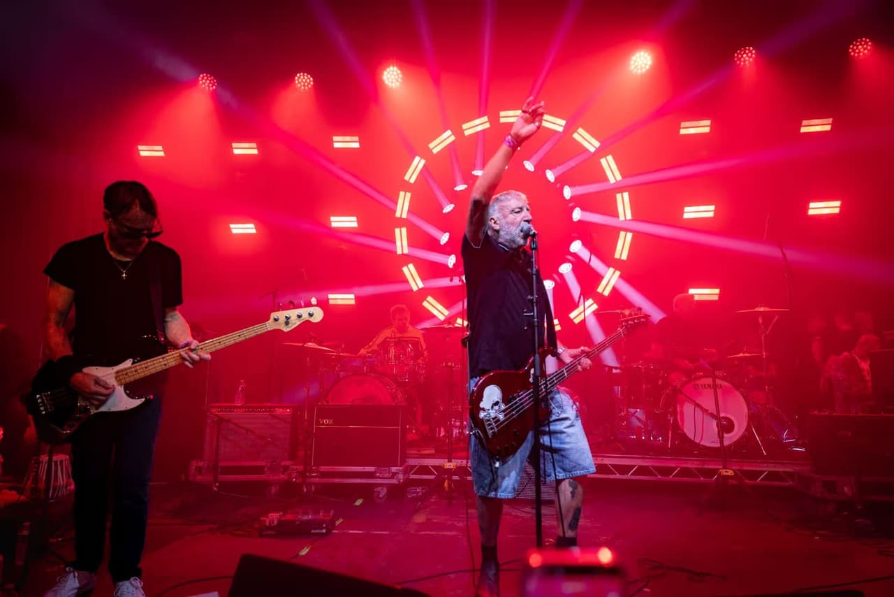 Peter Hook and band wide on stage, a spiral of red lights burning behind them.