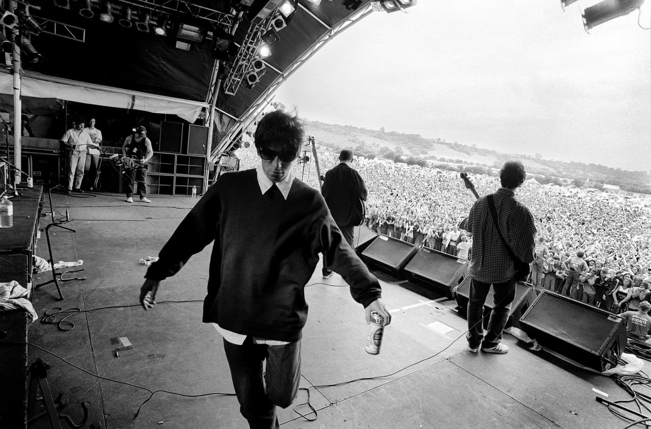 Black and white: the view from the stage, Liam Gallagher walking off with a can in hand, the festival crowd stretching to the hills.