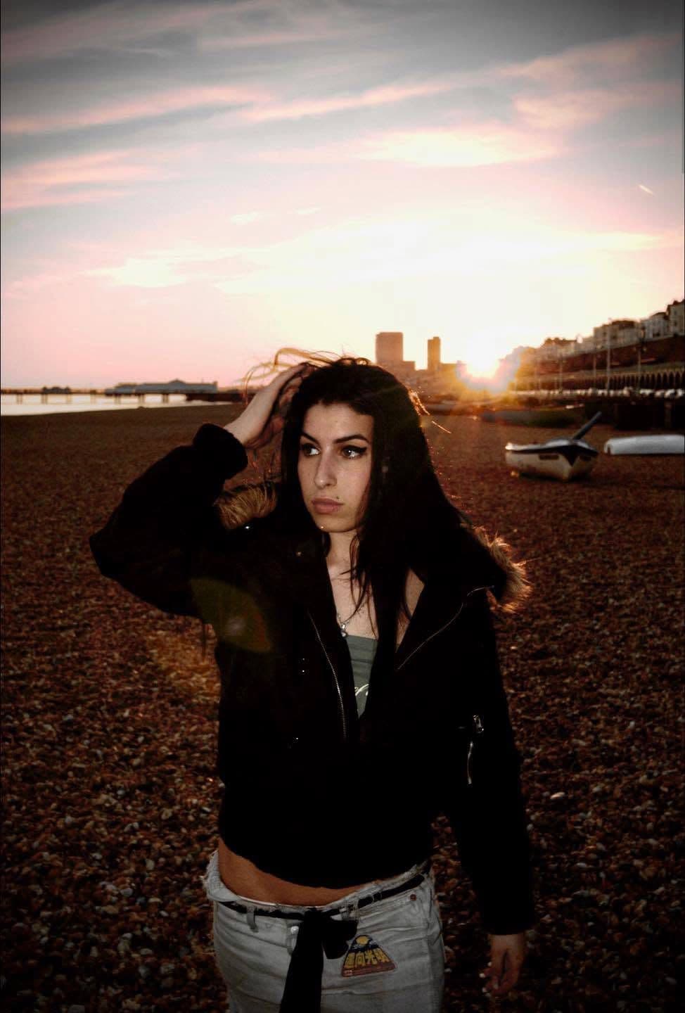 Amy Winehouse on Brighton beach at sunset, hand in her hair.