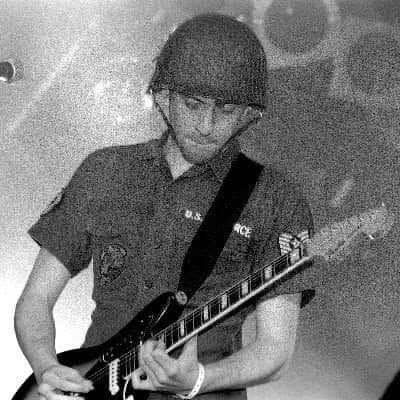 Black-and-white shot of a guitarist playing in an army helmet.