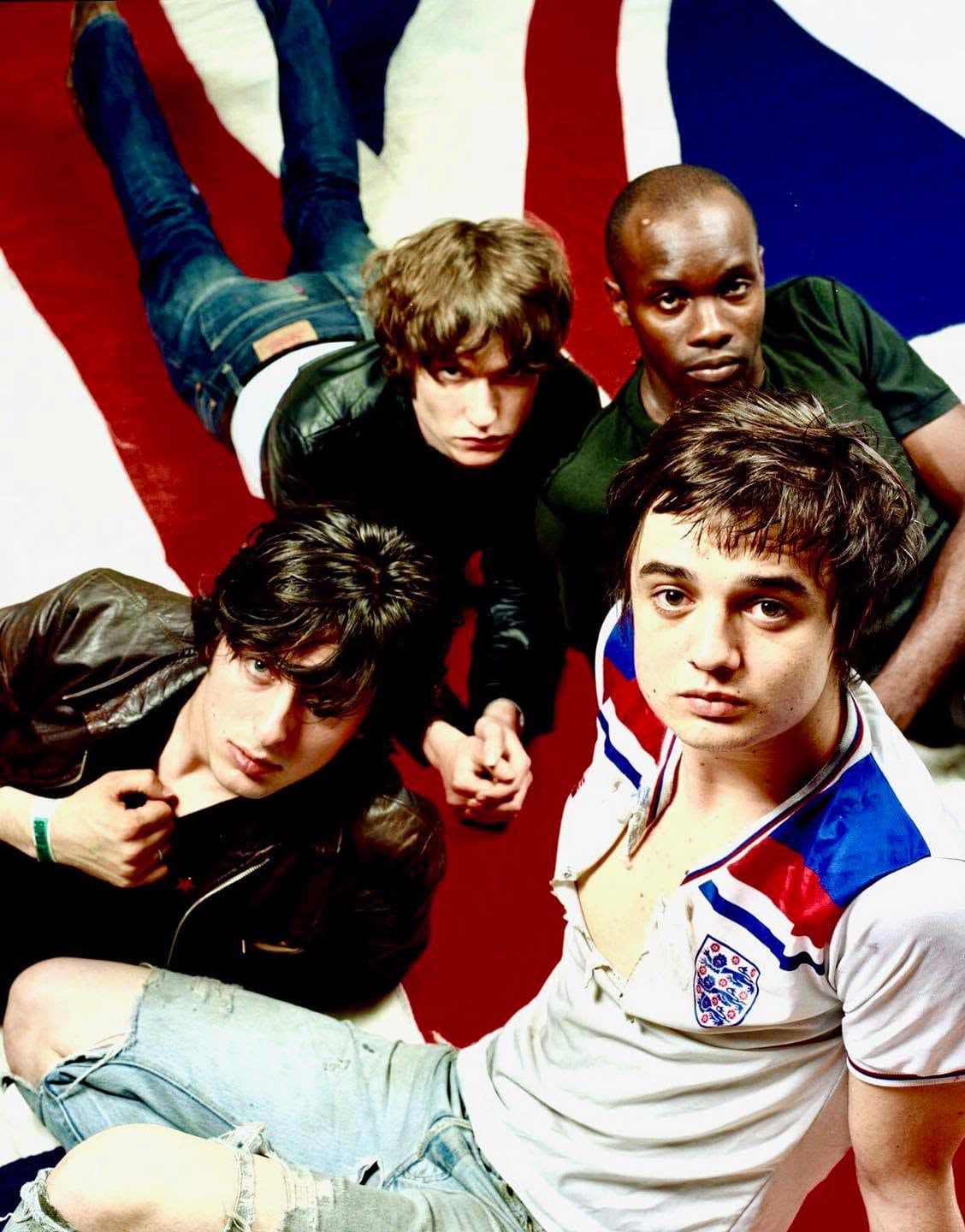 The Libertines gathered on a Union Jack flag, shot from above.