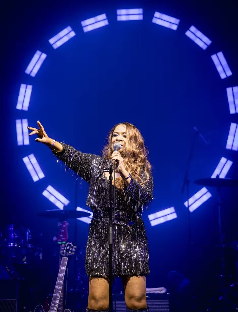 A singer in sequins in front of a circle of blue stage lights.